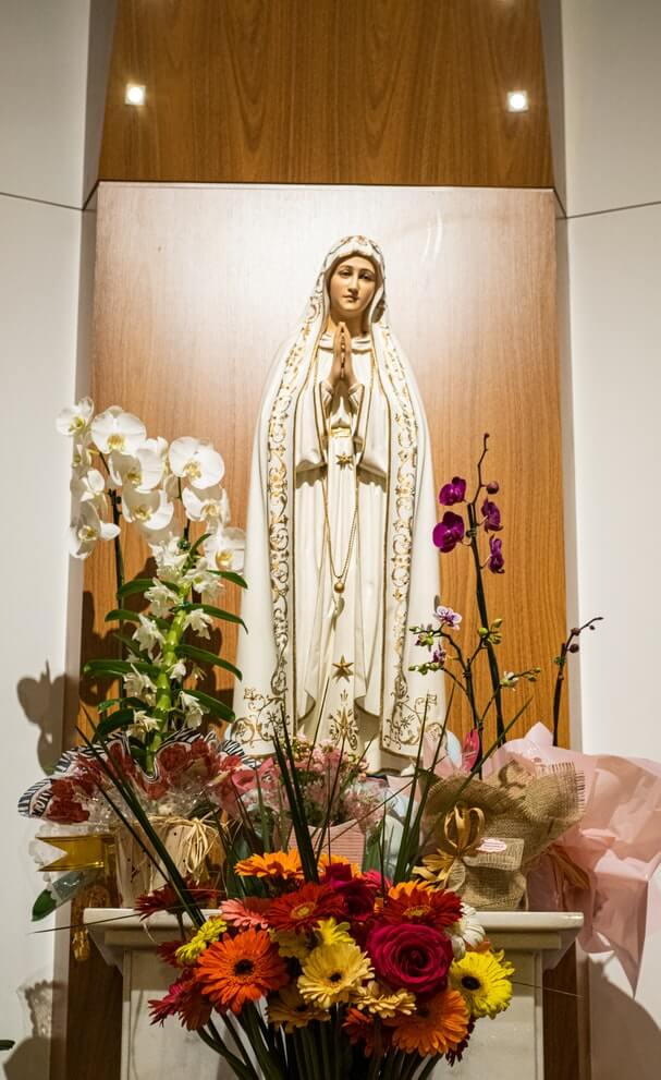 Flowers around a statue of Our Lady of Fatima